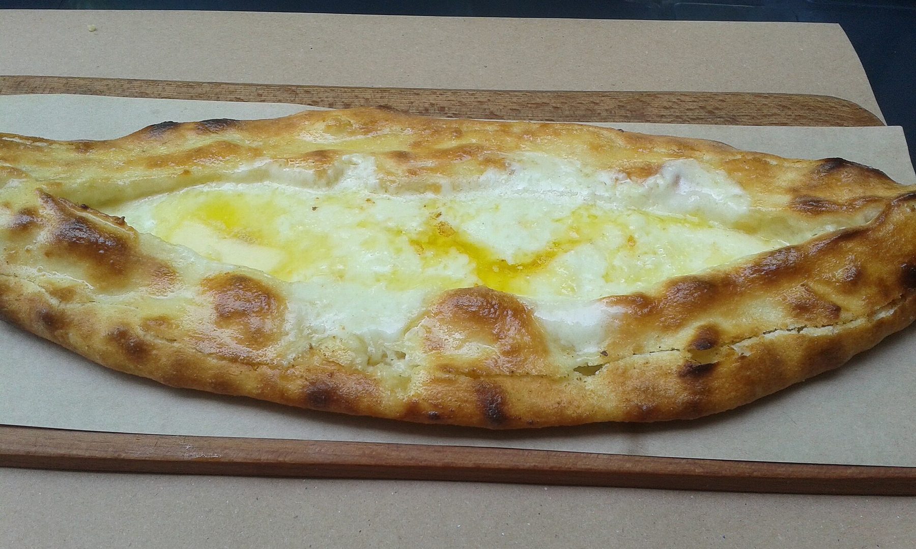 Tahta servis tahtasında, ortası yumurtalı peynirli Karadeniz pidesi